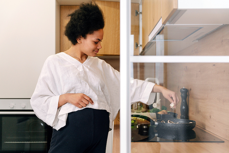 A pregnant person cooking in the kitchen