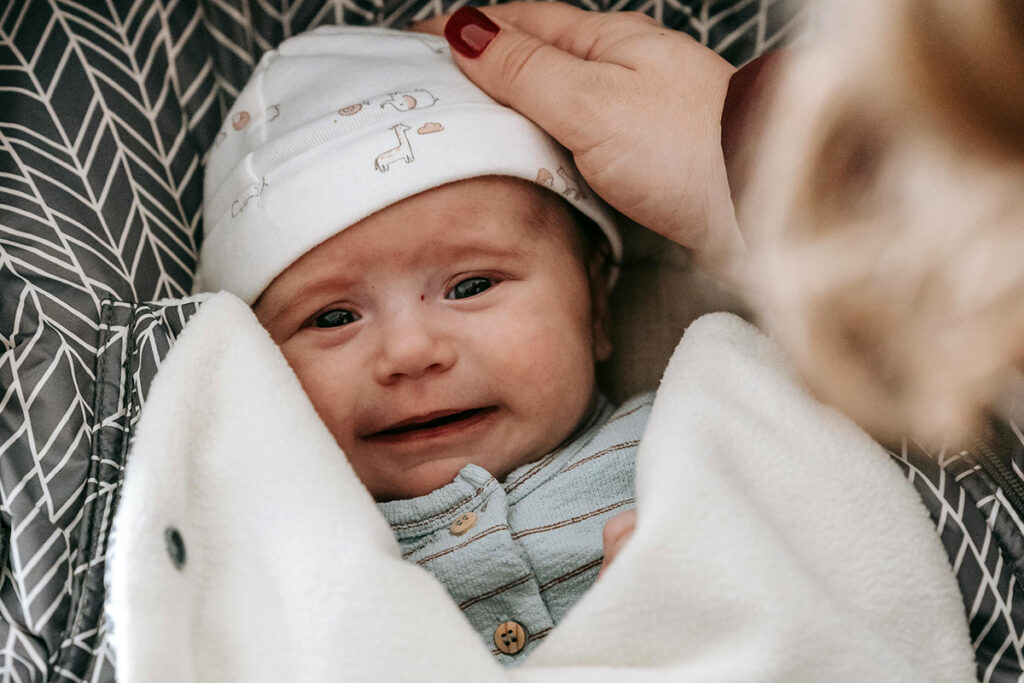 A baby being tucked in a car seat