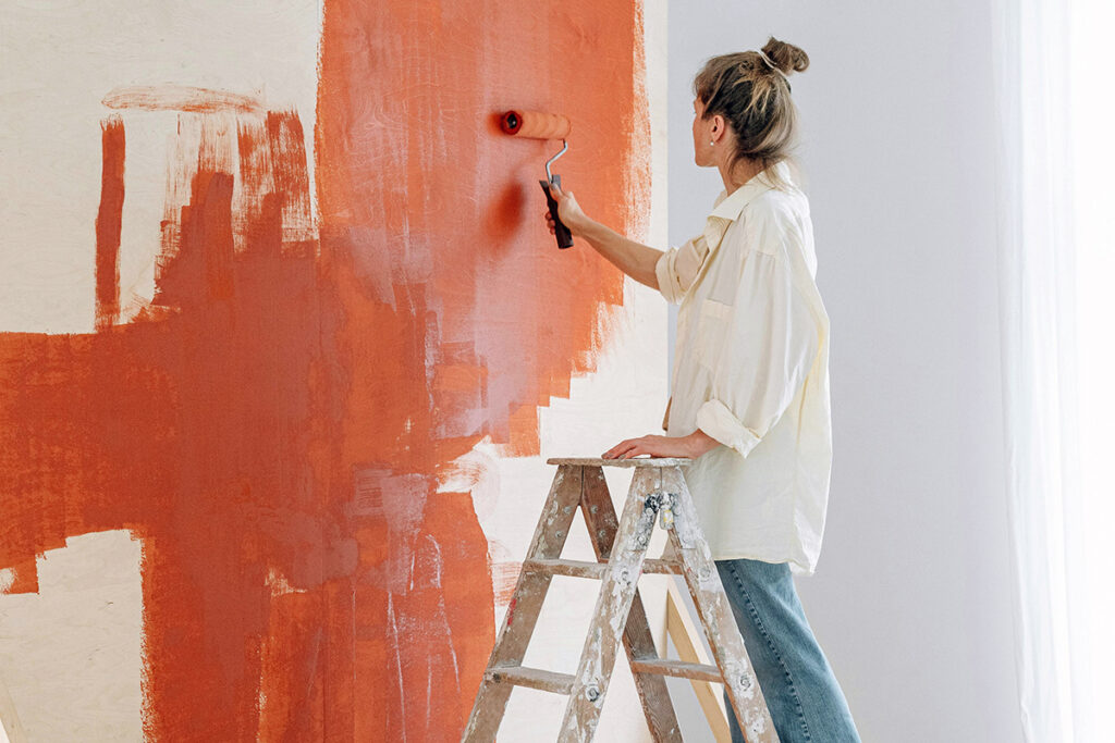 A person painting the wall rusty red