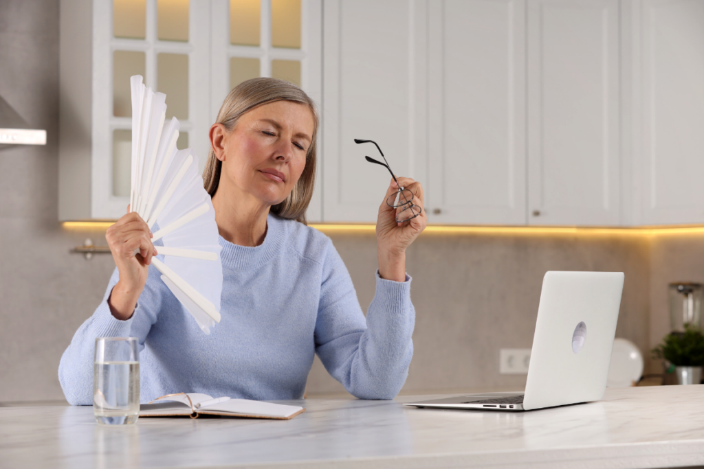 A person fanning her and looking at the laptop