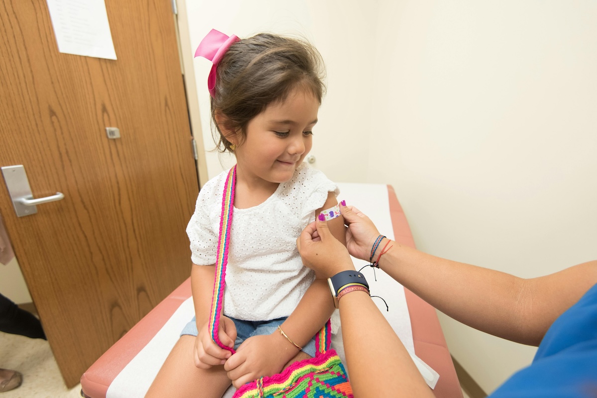 A kid getting a bandaid after a vaccine shot