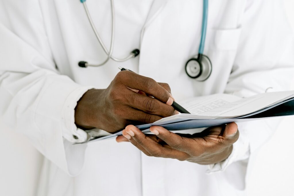 Male doctor with clipboard in his hands and stethoscope around his neck.