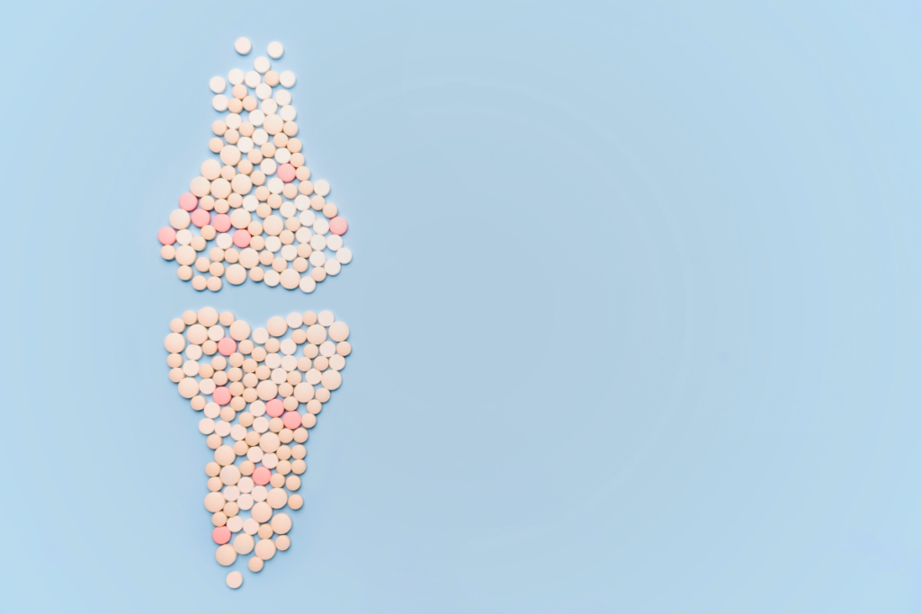 An assortment of pills arranged into the shape of bones on a blue background.