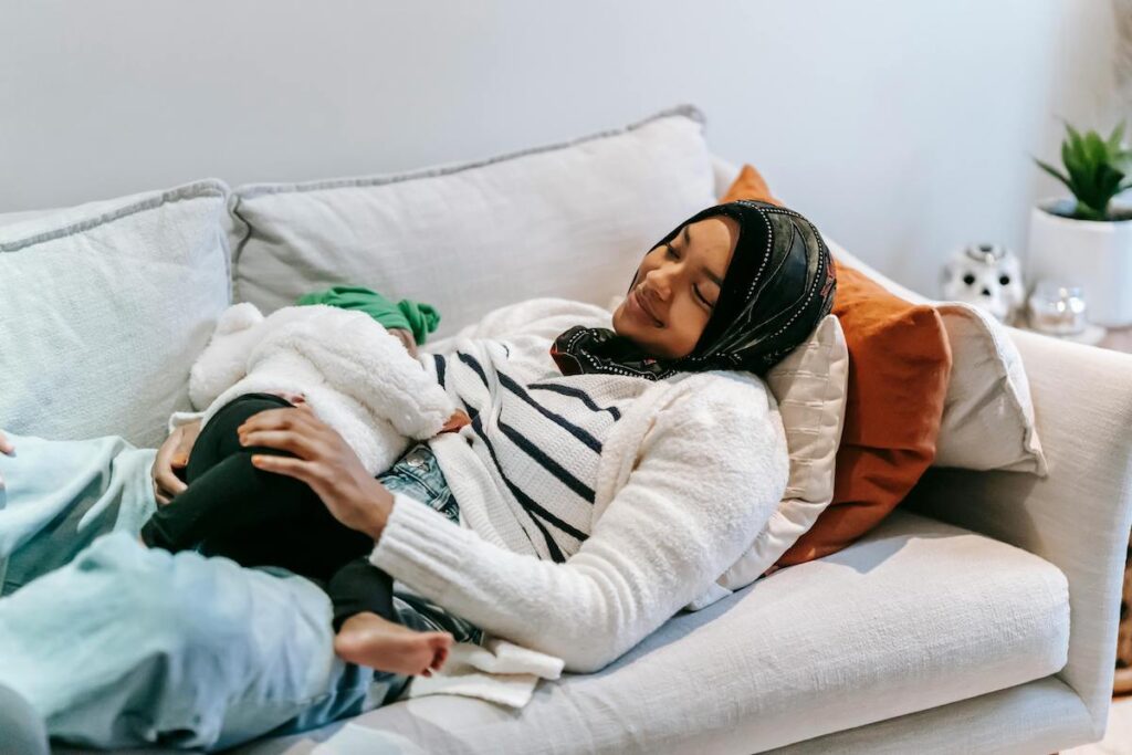 A parent breastfeeding her baby on a couch