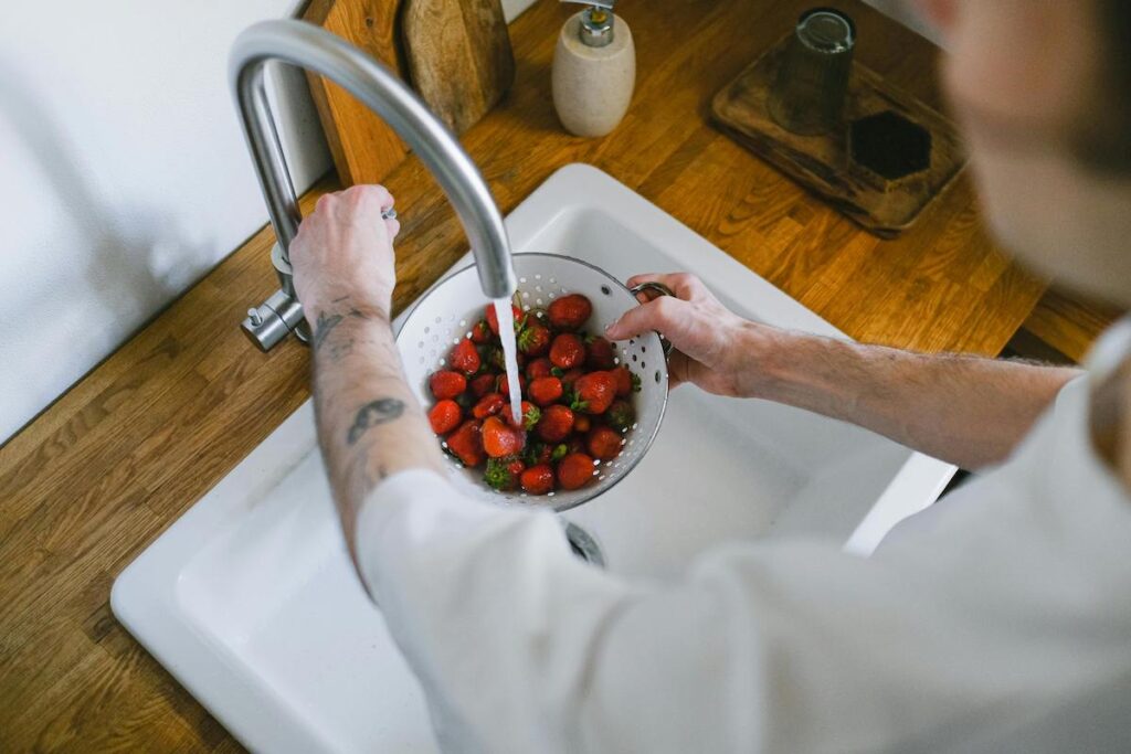 A person washing berries in the sink.