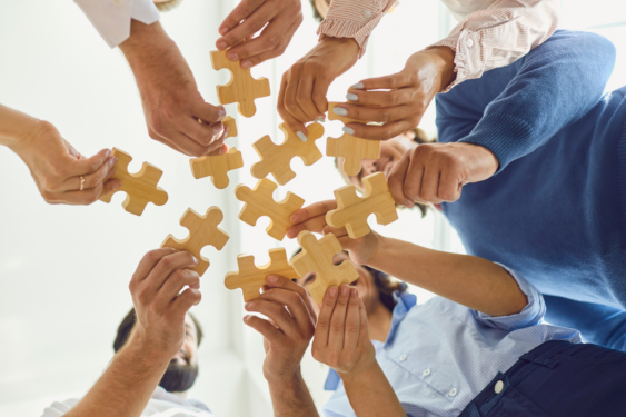 People standing in a circle and holding pieces of puzzles.