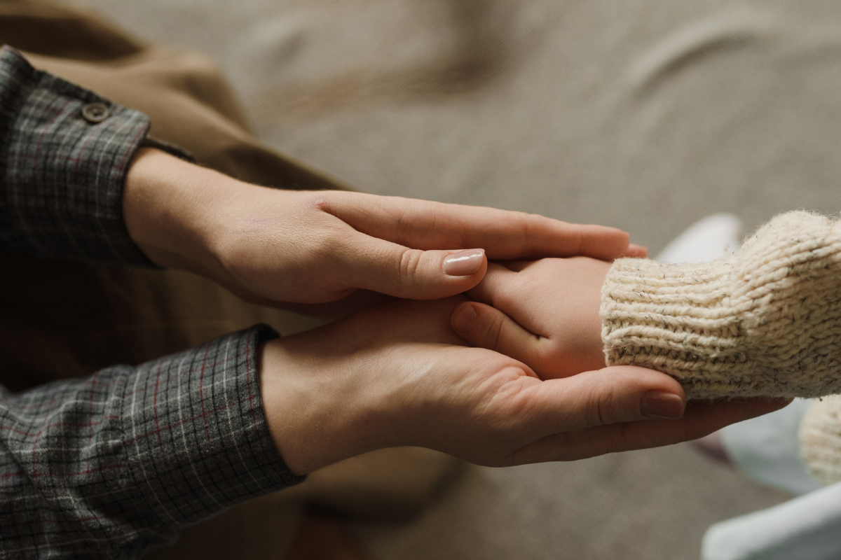 Adult hands holding a child's hand