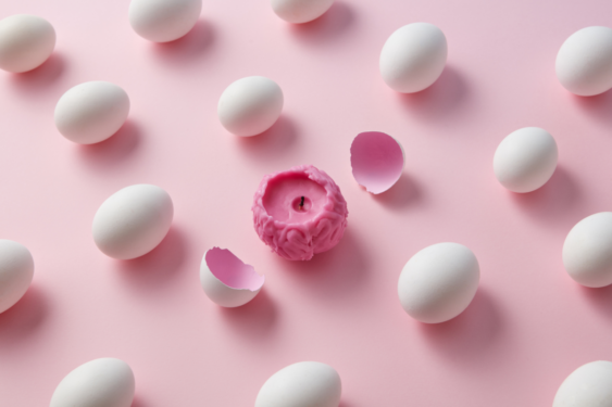 A brain shaped candle with eggs and egg shells around it.