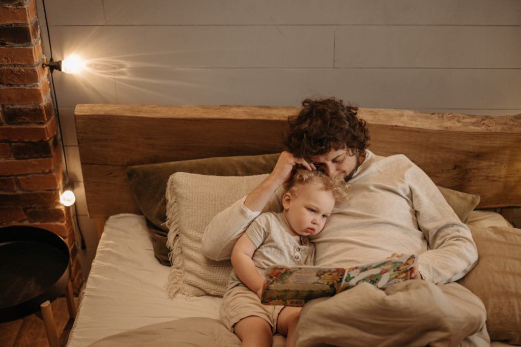 A parent reading a book to a child in bed.