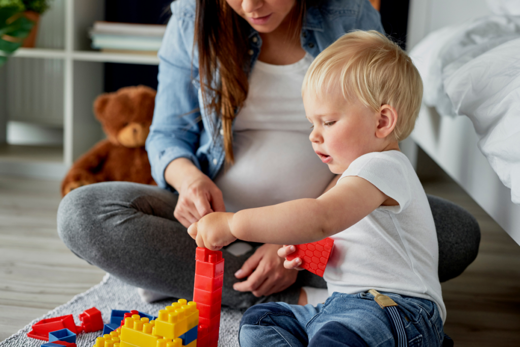 A pregnant person playing with her baby.