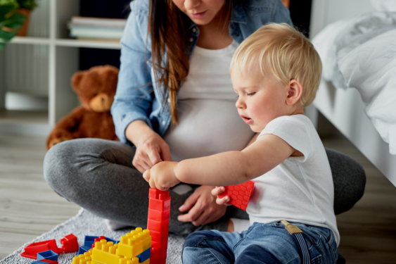 A pregnant person playing with her baby.