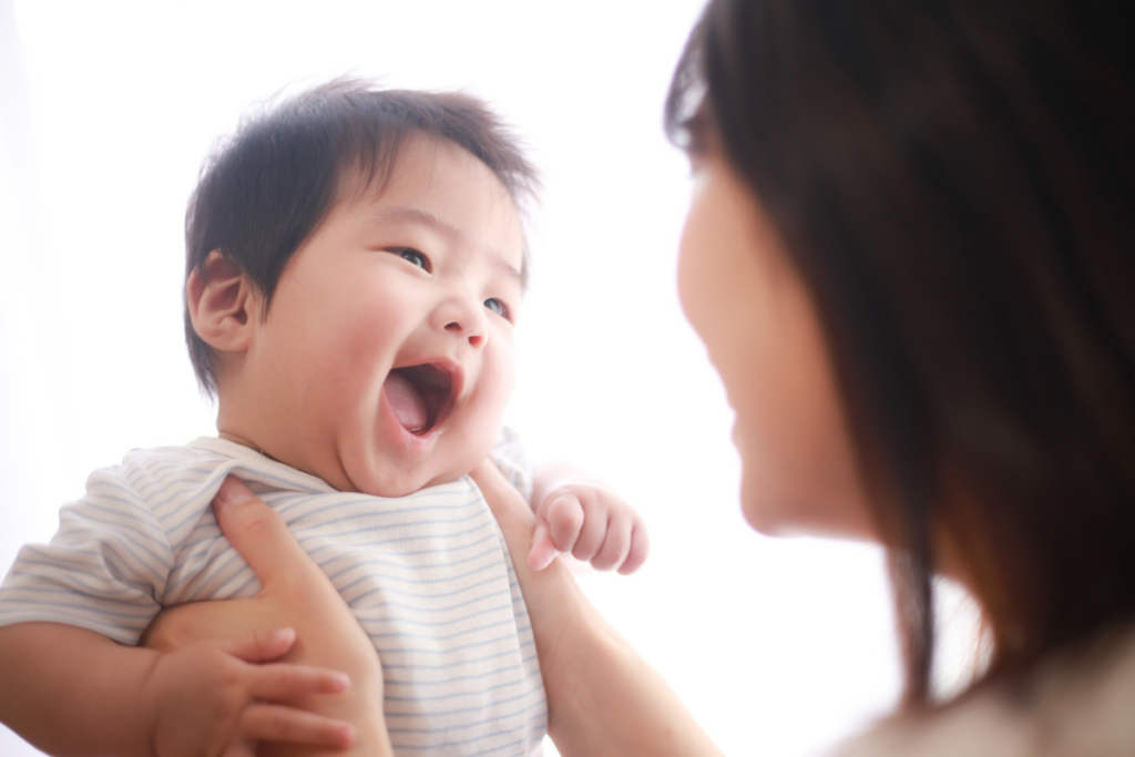 A baby laughing with his mother.