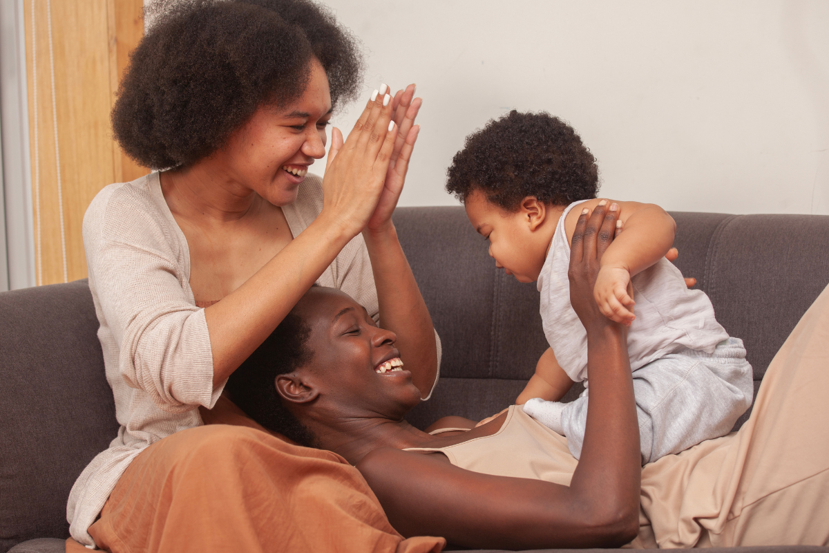 A queer couple playing with their baby.