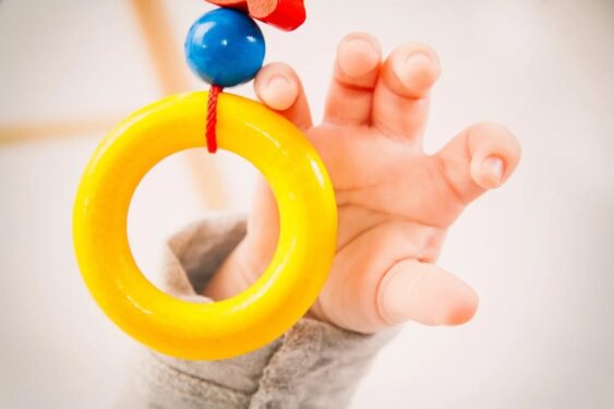 baby reaching for a ring toy