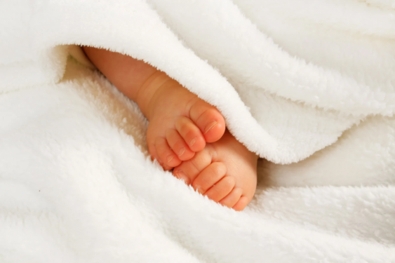 Newborn's feet under blanket.