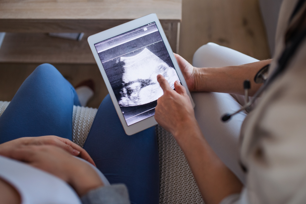 Unrecognizable Healthcare Worker with Ultrasound on Tablet and Pregnant Woman