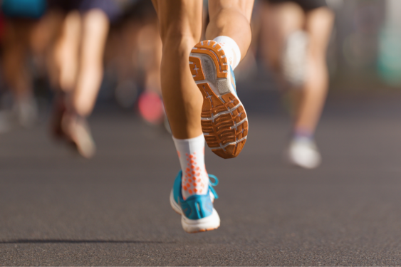 Legs of people running with one person's legs in focus.