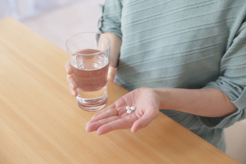 A person holding pills and water.