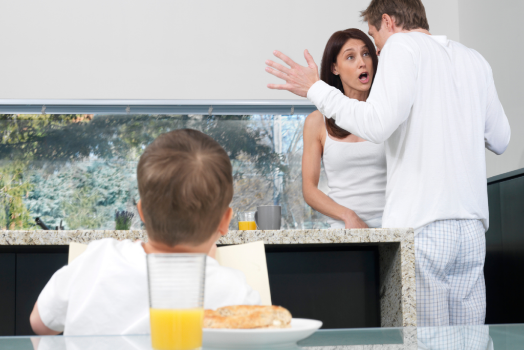 A toddler looking at parents fighting in the kitchen.