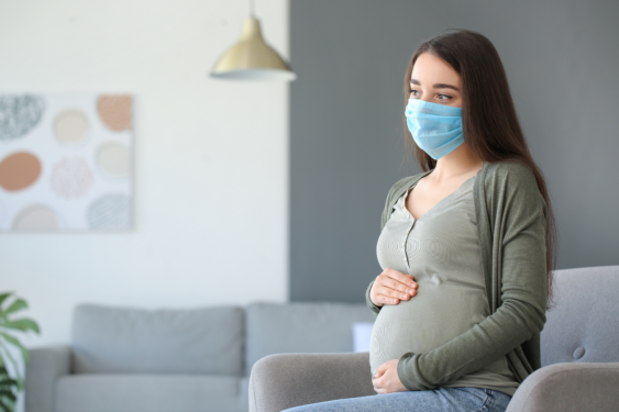 A pregnant person wearing a mask.