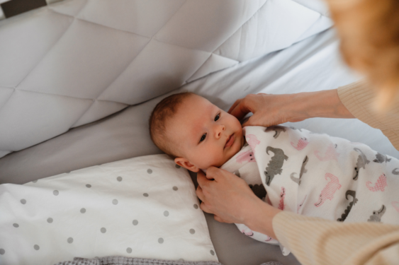 An infant swaddled by a parent.