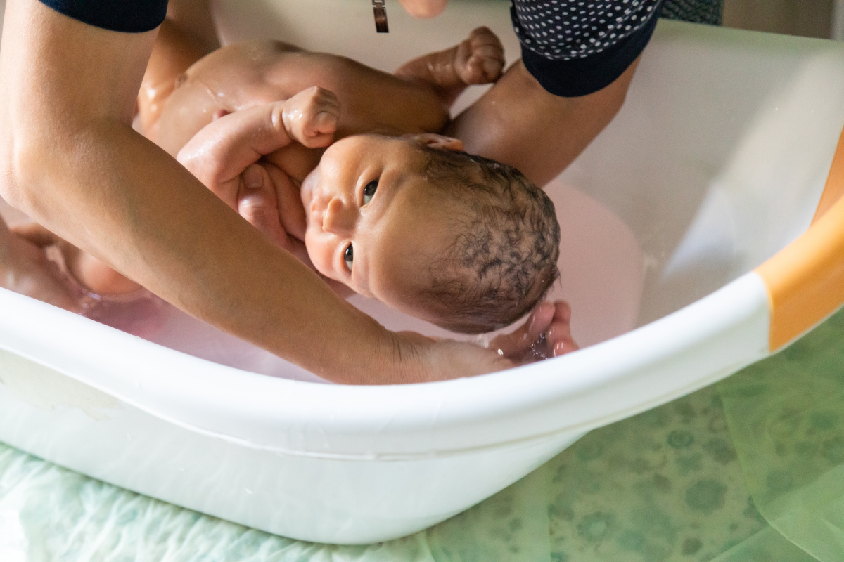 A person giving a bath to a newborn. 