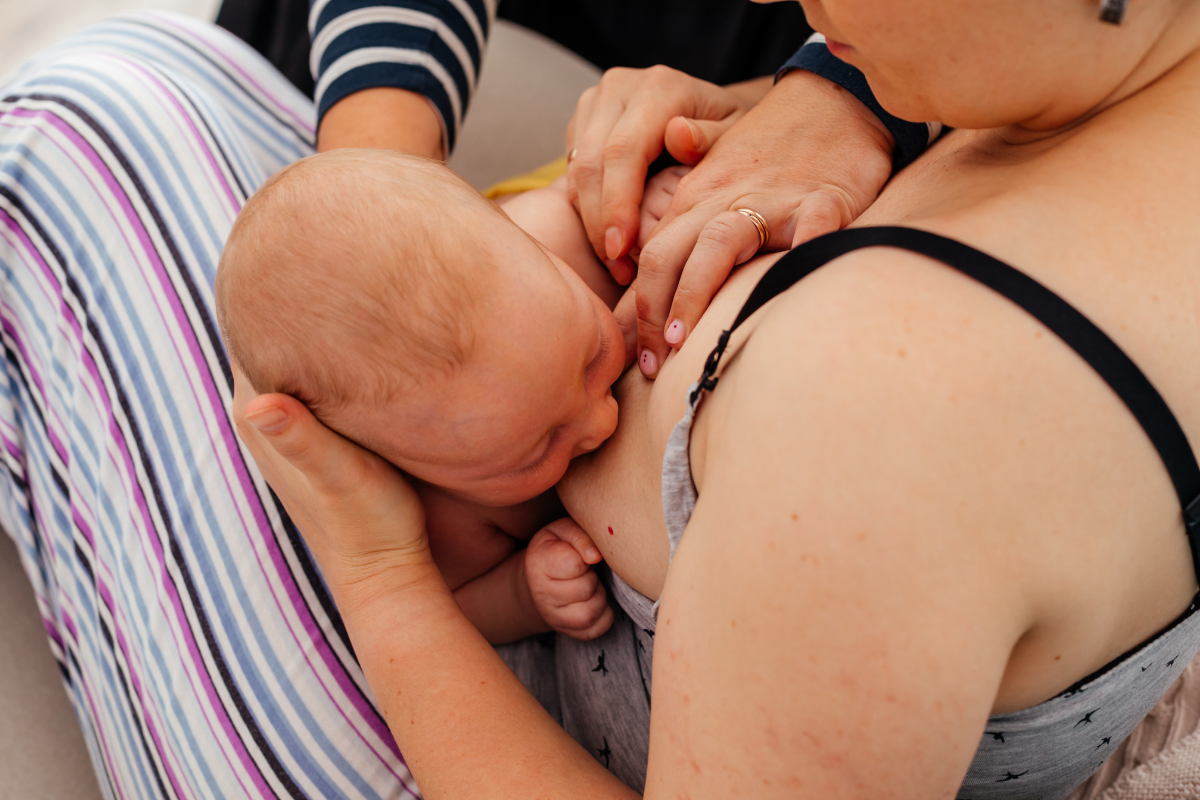 A person fixing the latch of a newborn while nursing.