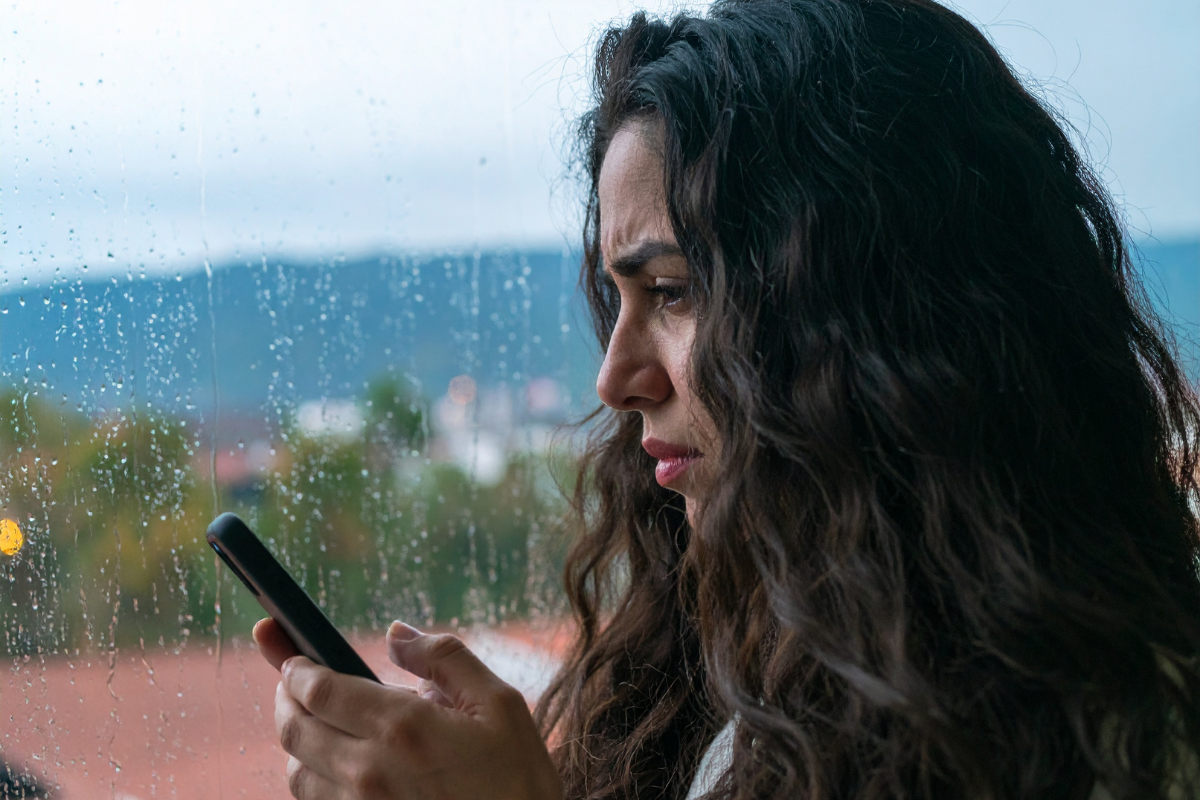 A person looking stressed and browsing through phone.