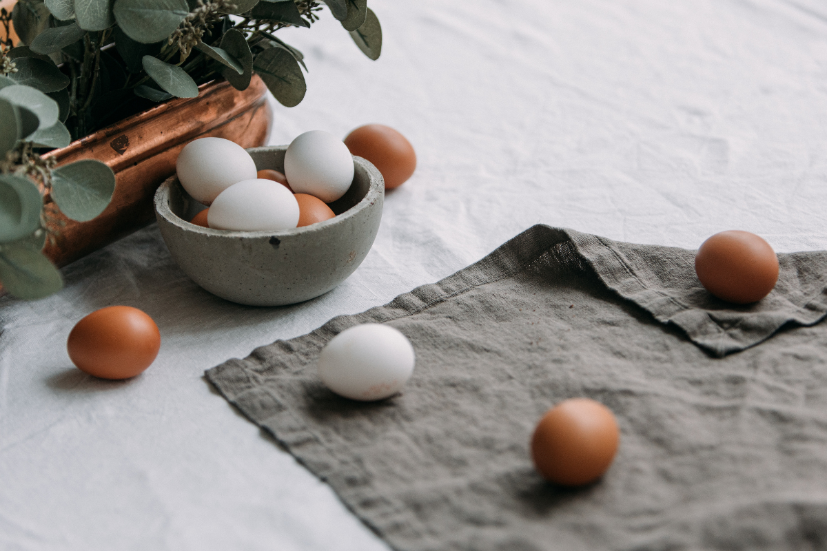 A basket of eggs and a few eggs scattered on the table.