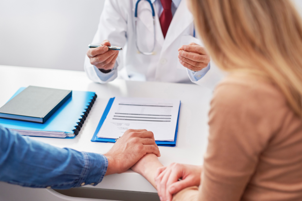 A couple in a doctor's office holding hands.
