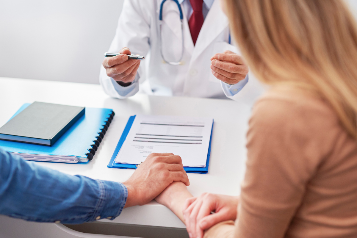 A couple in a doctor's office holding hands.