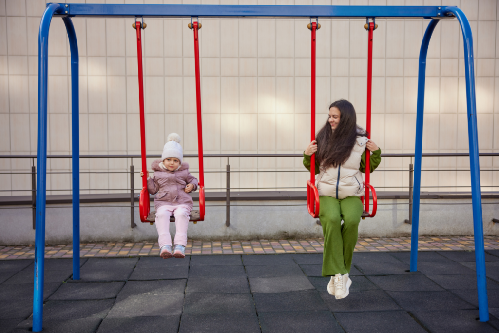 A mom and daughter on playground swings