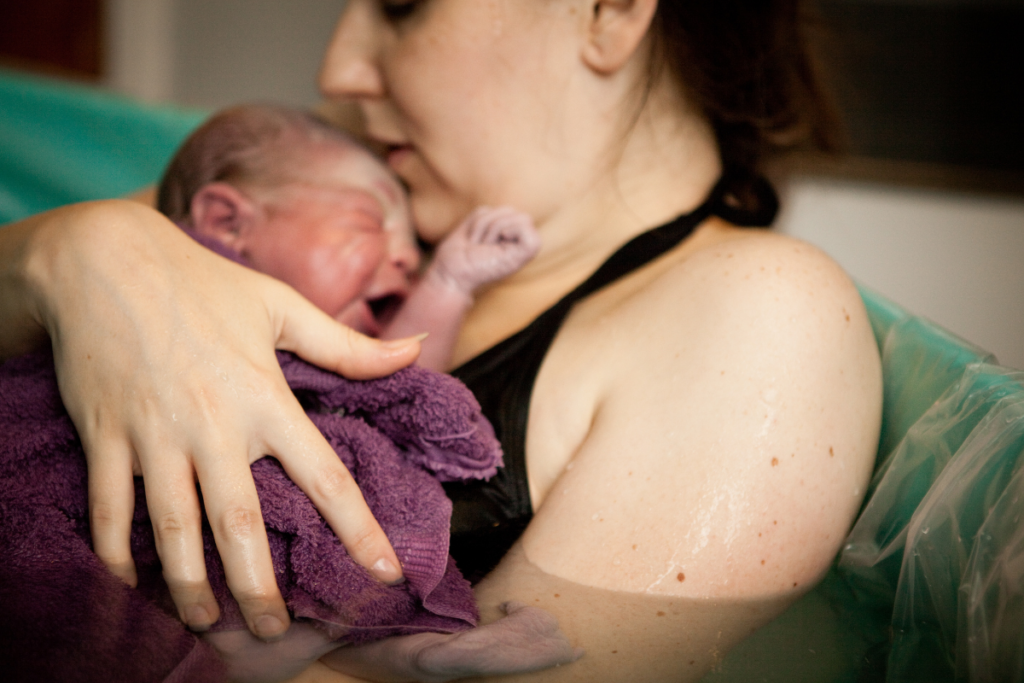 Woman holding baby on chest after water home birth
