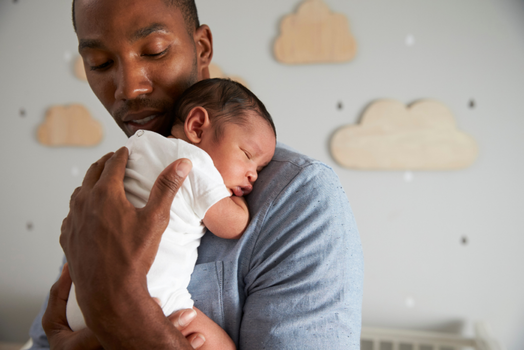 Father holding newborn baby sleeping on shoulder